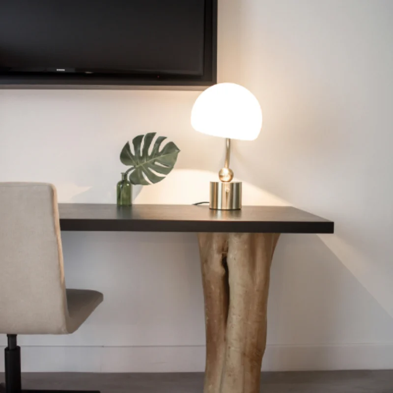 Modern hotel workspace with natural wood desk base, sculptural table lamp, and minimalist décor designed for comfort and style